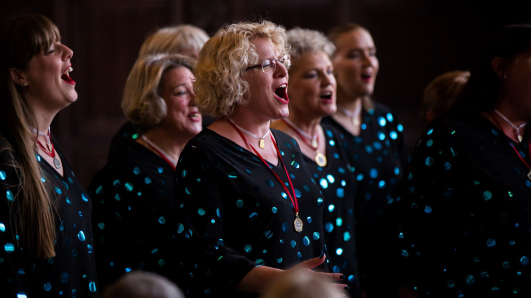 women singing in a group wearing matching black jumpers